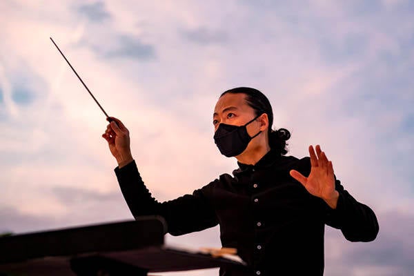 Student wearing mask conducting the Symphony Orchestra